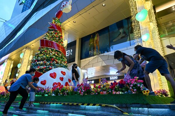 Люди стоят перед рождественскими декорациями на торговой улице в Сингапуре 14 декабря 2021 г. - Sputnik Узбекистан