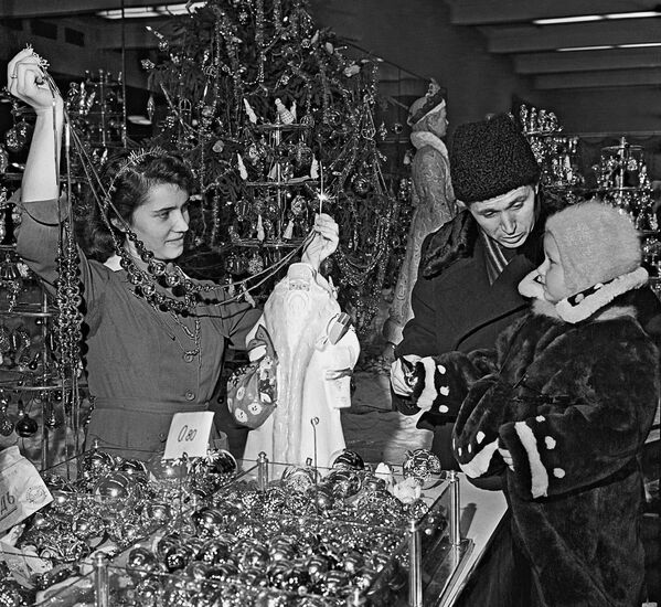 Папа с маленькой дочкой выбирают елочные украшения в магазине Детский мир в Москве в 1958 году. - Sputnik Узбекистан