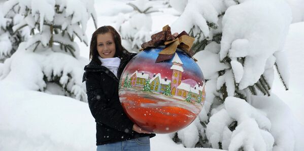 Девушка держит самый большой стеклянный ёлочный шар, который выдули вручную, изготовленный компанией  Joska Kristall в Богемии. Весит шар пять килограммов, его диаметр 60 сантиметров. - Sputnik Узбекистан