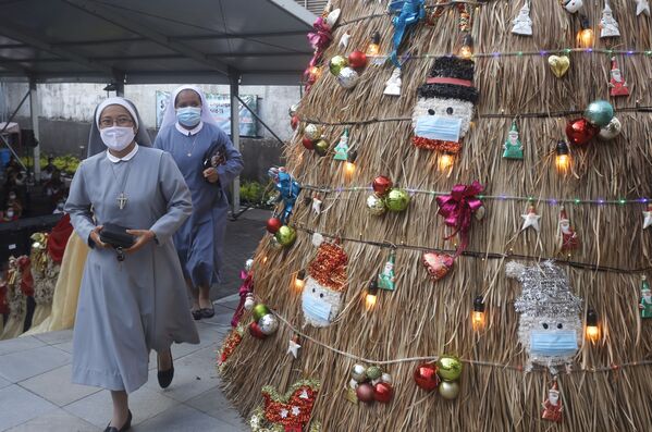 Монахини в церкви на Бали проходят мимо импровизированной ёлки с украшениями в &quot;пандемийной&quot; тематике. - Sputnik Узбекистан