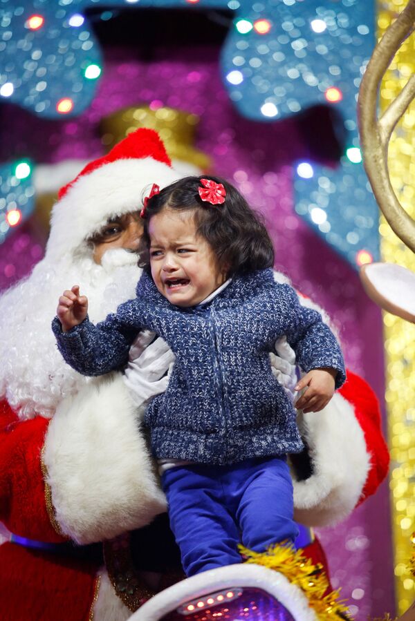 Девочка испугалась мужчину в костюме Санта-Клауса на рождественской ярмарке в Мехико, 22 декабря 2021 г. - Sputnik Узбекистан