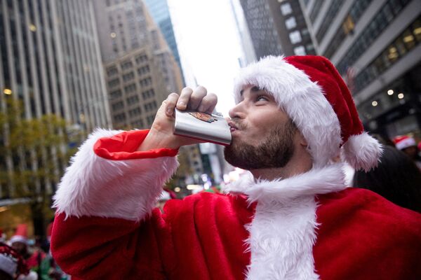 Прохожий в костюме Санта-Клауса пьет из фляжки во время фестиваля SantaCon в Нью-Йорке11 декабря 2021 г. - Sputnik Узбекистан