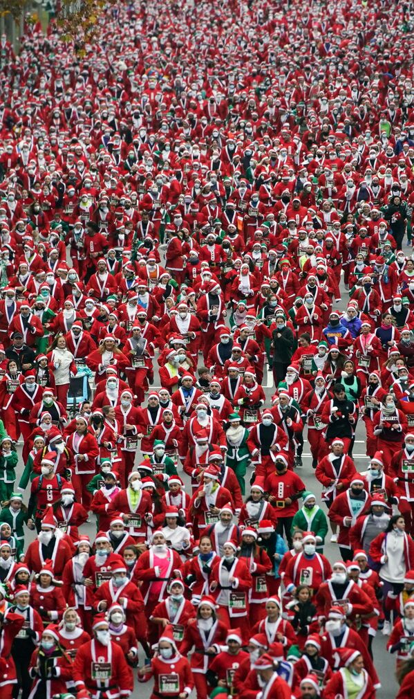 Люди в костюмах Санта-Клаусов во время благотворительного забега в пользу пострадавших от извержения вулкана Кумбре Вьеха в Мадриде, 19 деаабря 2021 г. - Sputnik Узбекистан
