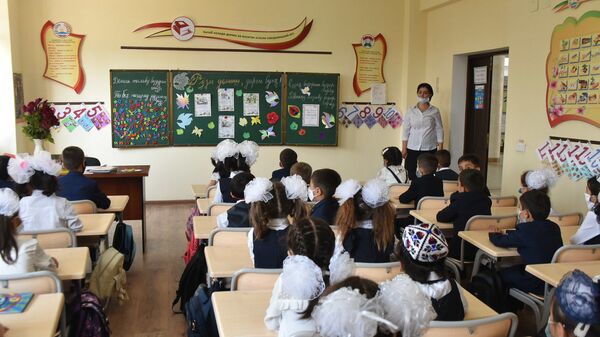 Школьники сидят за партой в защитных масках - Sputnik Ўзбекистон