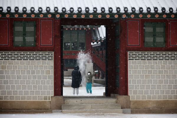 Ребенок играет в снегу во дворце Деоксу в Сеуле, Корея, 19 января 2022 г.  - Sputnik Узбекистан