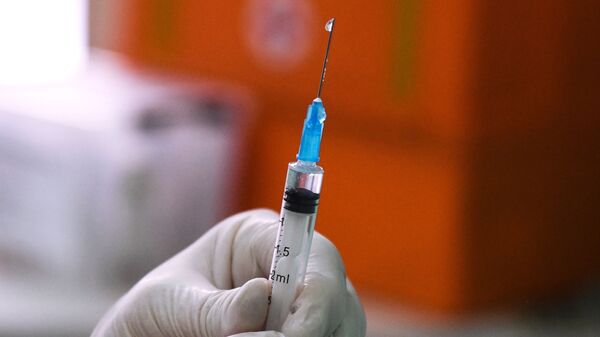 Медицинский сотрудник держит в руках шприц с вакциной от COVID-19 - Sputnik Узбекистан