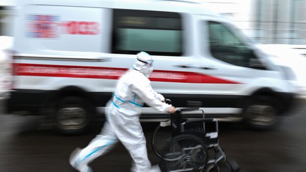 Медицинский работник возле автомобиля скорой помощи на территории городской клинической больницы №40 в Коммунарке - Sputnik Ўзбекистон