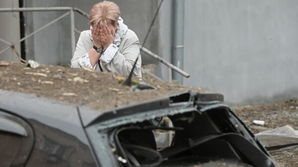 Жительница во дворе жилого дома, подвергшегося обстрелу, в Киевском районе Донецка. - Sputnik Ўзбекистон