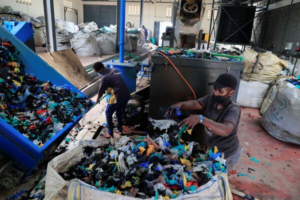 Работники очищают пластиковые пакеты на заводе по переработке пластика возле свалки Дандора. - Sputnik Узбекистан