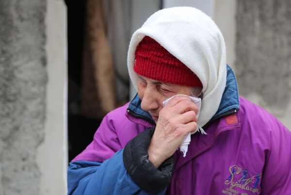 Пожилая женщина плачет около жилого дома в Киевском районе Донецка, разрушенном в результате обстрела - Sputnik Узбекистан