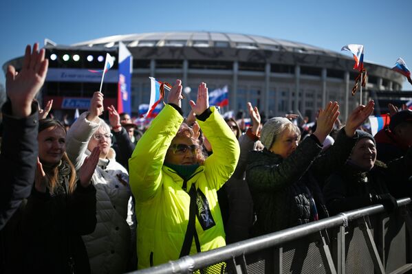 Люди смотрят трансляцию митинга-концерта, посвященного воссоединению Крыма с Россией, у большой спортивной арены Лужники в Москве - Sputnik Узбекистан