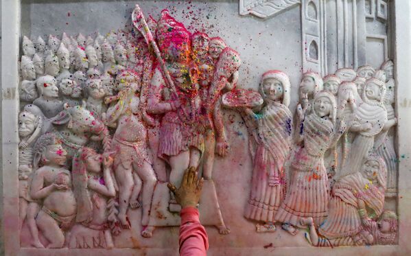 Мужчина посыпает цветным порошком религиозные фрески во время молитвы в помещении храма в старых кварталах Дели. - Sputnik Узбекистан