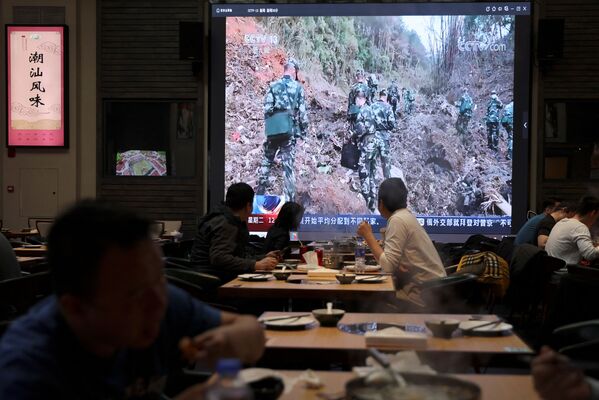 Новости о работе спецслужб на месте крушения транслируются на экране в кафе. - Sputnik Узбекистан