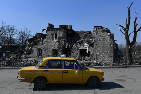 Автомобиль проезжает мимо разрушенного дома в Волновахе - Sputnik Узбекистан