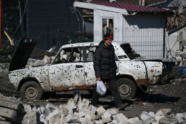 Житель Волновахи проходит мимо автомобиля, поврежденного обстрелами города. - Sputnik Узбекистан