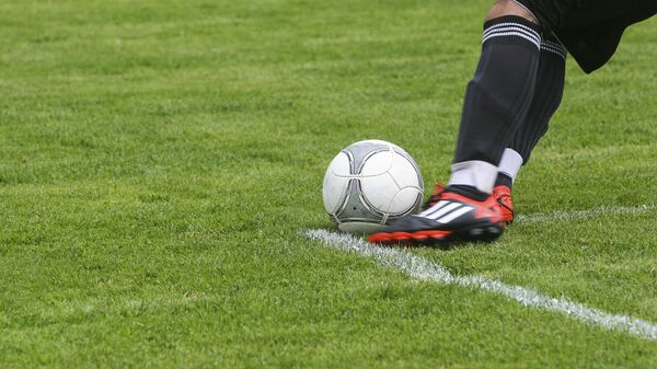 Футболист ногами белый серый футбольный мяч на поле зеленой травы - Sputnik Узбекистан