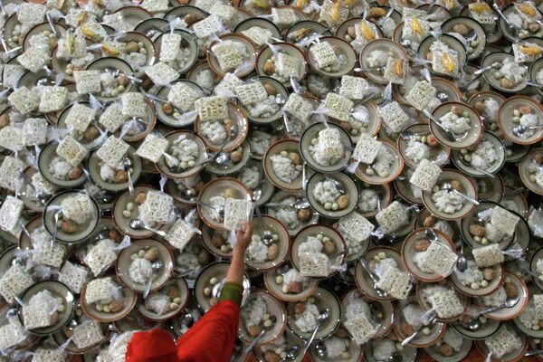 Женщины готовят тарелки с едой для бесплатной раздачи верующим в Индонезии. - Sputnik Узбекистан