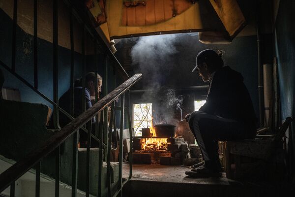 Местные жители готовят еду на лестничном пролете в подъезде своего дома в Мариуполе - Sputnik Узбекистан