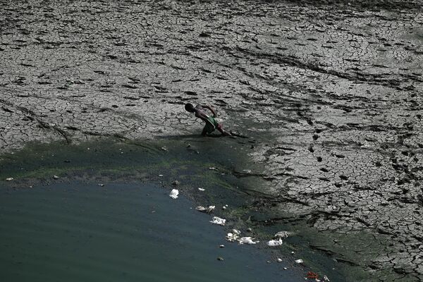 Мальчик идет по пересохшему руслу реки Ямуна в жаркий день в Нью-Дели, Индия. - Sputnik Узбекистан