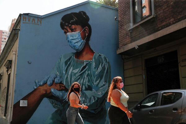 Женщины проходят мимо фрески с изображением медсестры в Сантьяго,  Чили. - Sputnik Узбекистан