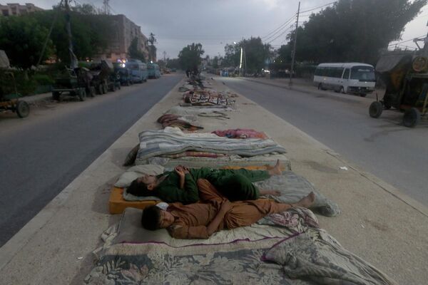 Рабочие спят посреди дороги ранним утром в портовом городе Карачи, не выдержав сильной жары, которая на протяжении нескольких дней продолжается в Пакистане. - Sputnik Узбекистан
