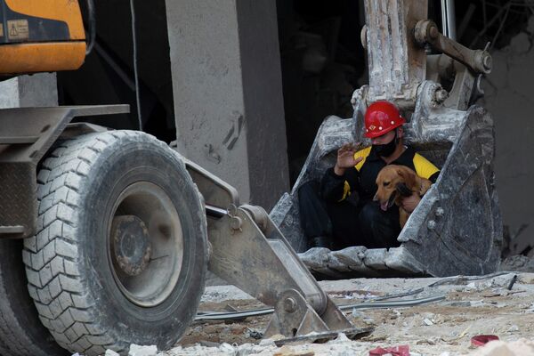Спасателя и его поисковую собаку перевозят с помощью землеройной машины после взрыва в кубинской Гаване, разрушившего здание гостиницы Saratoga. - Sputnik Узбекистан