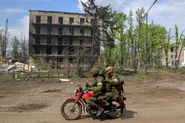 Военнослужащие едут на мотоцикле мимо разрушенных домов в городе Попасная - Sputnik Узбекистан