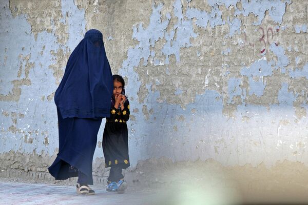Женщина в бурке идет по улице с маленькой девочкой в хиджабе. - Sputnik Узбекистан