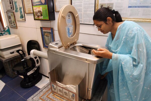 На этой архивной фотографии, сделанной 27 октября 2007 года, сотрудница Международного музея туалетов в Индии демонстрирует туалет, сжигающий отходы нажатием одной кнопки. С одной стороны, музей кажется странным, с другой — он помогает специалистам в области гигиены исследовать санитарные технологии. - Sputnik Узбекистан