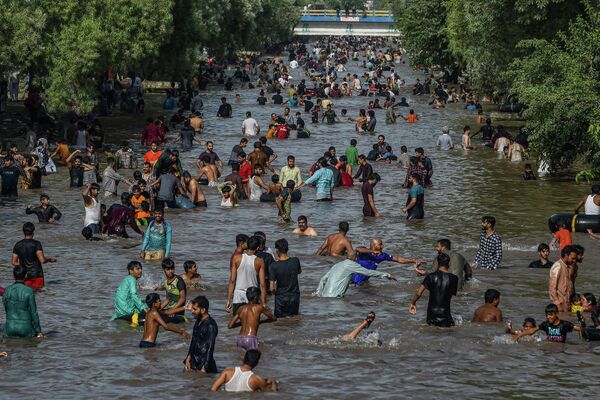 Люди охлаждаются в канале в жаркий летний день в Лахоре, Пакистан. - Sputnik Узбекистан