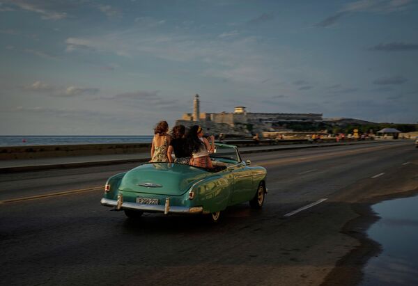 Туристы едут по Малекону на старинном американском автомобиле в Гаване, Куба. - Sputnik Узбекистан