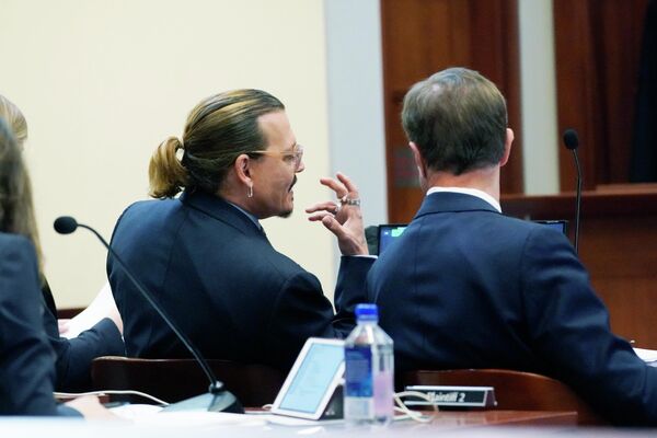 Актер Джонни Депп разговаривает со своим адвокатом Беном Чу в зале суда округа Фэрфакс, штат Вирджиния, 23 мая 2022 года. - Sputnik Узбекистан