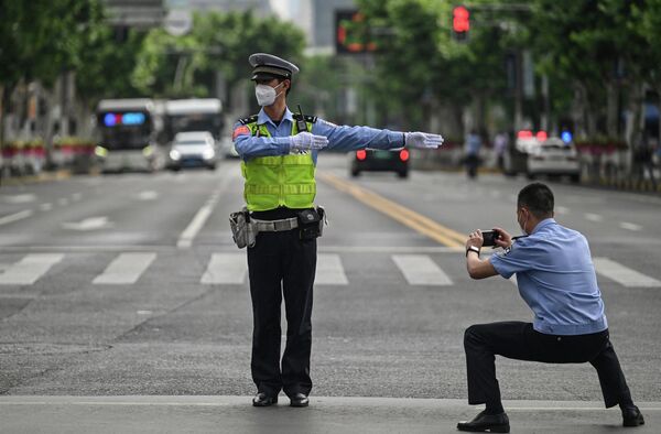 Офицер фотографирует другого офицера, контролирующего движение в районе Цзинъань в Шанхае 1 июня 2022 года, после окончания блокировки, из-за которой в городе два месяца действовали жесткие ограничения. - Sputnik Узбекистан
