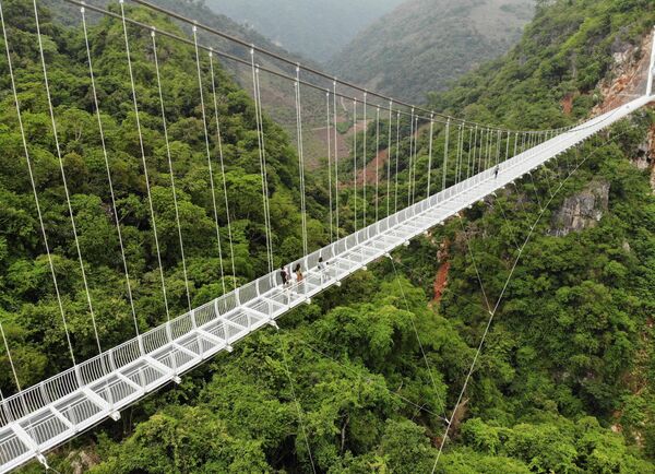 На этом аэрофотоснимке виден недавно построенный стеклянный мост Бах Лонг в районе Мок Чау во вьетнамской провинции Сон Ла, 29 апреля 2022 года. Мост со стеклянным дном, подвешенный на высоте около 150 метров над ущельем, покрытым джунглями. - Sputnik Узбекистан