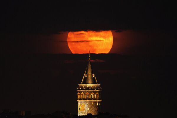 Суперлуна восходит за Галатской башней в Стамбуле, Турция, во вторник, 14 июня 2022 года. Луна достигла своего полного состояния во вторник во время явления, известного как суперлуние из-за его близости к Земле, и оно также обозначено как &quot;клубничная луна&quot;, потому что это полнолуние во время сбора урожая клубники. - Sputnik Узбекистан