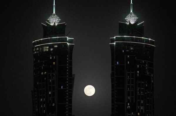 Полная луна восходит между двумя башнями в Дубае, Объединенные Арабские Эмираты, вторник, 14 июня 2022 года. - Sputnik Узбекистан