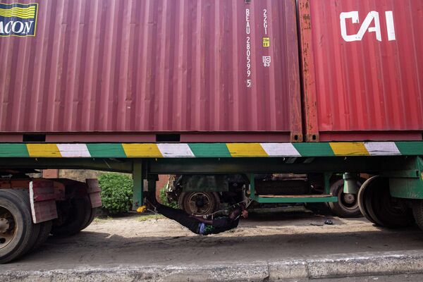 Водитель спит под своим грузовиком, припаркованным на обочине дороги, в ожидании доступа в порт Тинкан в Лагосе, 11 января 2021 года. - Sputnik Узбекистан