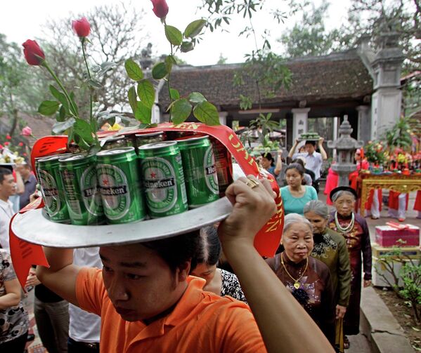 Мужчина несет банки с пивом на алтарь в буддийском храме Ким Лиен во Вьетнаме во время праздника. - Sputnik Узбекистан