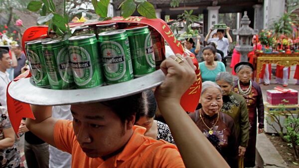 Мужчина несет банки пива  к алтарю во время фестиваля Kim Lien Temple в Ханое, Вьетнам - Sputnik Узбекистан