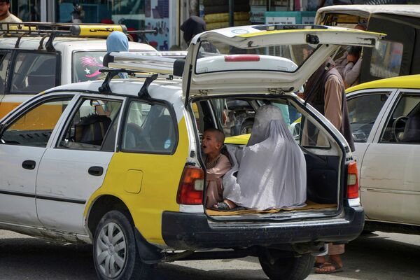 Женщина с ребенком ожидает на заднем сиденье такси, чтобы добраться до Кандагара. - Sputnik Узбекистан