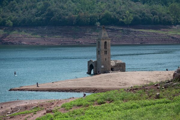 На этой фотографии, сделанной 23 августа 2022 года, показан общий вид на болото Сау и руины церкви Сант-Рома-де-Сау, расположенной в провинции Жирона в Каталонии. Болото Сау – это водохранилище на реке Тер, созданное плотиной, расположенной в муниципалитете Виланова-де-Сау. Болото, построенное с 1947 по 1962 год, покрывало деревню Сант-Рома-де-Сау, которая все еще видна, включая колокольню романской церкви 11 века, когда уровень воды в водохранилище низкий. Церковь на болоте Сау зарегистрирована как старейшая в мире, сохранившаяся в вертикальном положении в воде. - Sputnik Узбекистан
