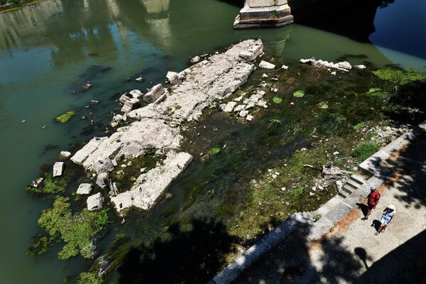 На этом снимке, сделанном 2 июля 2022 года в Риме, виден низкий уровень воды в реке Тибр возле моста Виктора Эмануэле II, на котором виден древний мост, построенный при римском императоре Нероне (внизу). - Sputnik Узбекистан