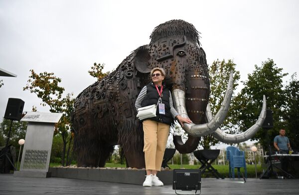 Участница Восточного экономического форума во Владивостоке фотографируется у скульптуры мамонта - Sputnik Узбекистан