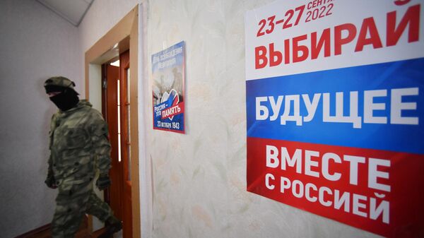 Участник добровольческого отряда на избирательном участке во время голосования на референдуме о присоединении Запорожской области к России в Мелитополе - Sputnik Узбекистан