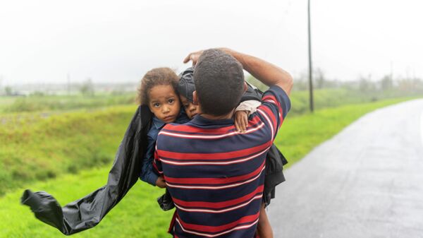 Мужчина несет двоих детей под дождем в поисках убежища после того, как ураган Иэн затопил их дом в Пинар-дель-Рио, Куба - Sputnik Ўзбекистон