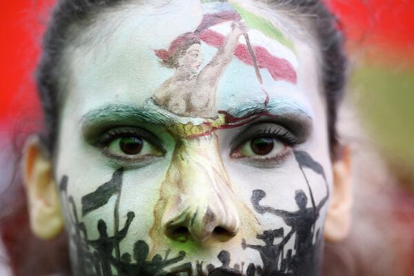Девушка с раскрашенным лицом, изображающим Свободу, ведущую народ, на демонстрации в поддержку курдской женщины Махсы Амини во время акции протеста на площади Республики в Париже. - Sputnik Узбекистан