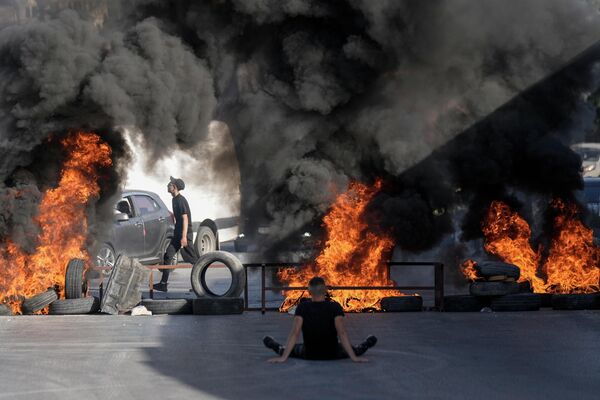 Горящие шины на месте, где двое палестинцев были застрелены израильской армией в лагере беженцев Джалазон недалеко от города Рамалла. - Sputnik Узбекистан
