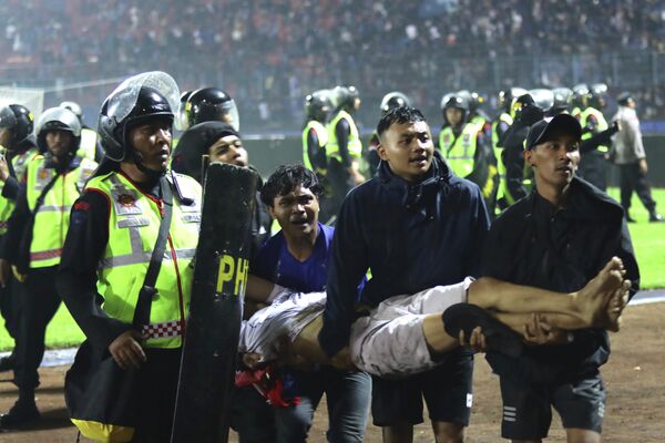 Футбольные болельщики несут раненого после столкновений во время футбольного матча на стадионе Канжурухан в Маланге, Восточная Ява, Индонезия. - Sputnik Узбекистан