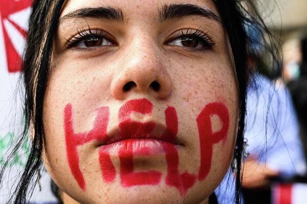Молодая женщина с надписью HELP на лице принимает участие в акции протеста в Риме в память о смерти курдской женщины Махсы Амини в Иране. - Sputnik Узбекистан