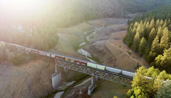 Поезд проезжает по мосту над пересохшей рекой в Калифорнии.  - Sputnik Узбекистан